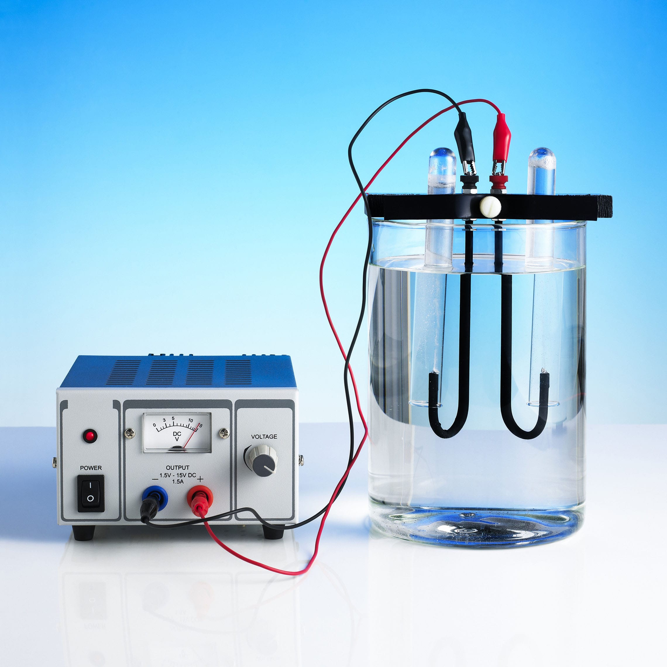 Elektrolizom vode nastaju vodik i kisik.; Na fotografiji se vidi uređaj za proizvodnju struje .Žice su mu uronjene u posudu s vodom.