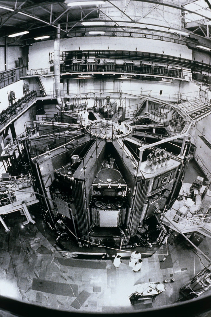 Crno bijela fotografija prikazuje pogled na fuzijski reaktor pod nazivom Tokamak. Tokamak je veliki rotacijski stroj za proizvodnju toroidalnog magnetskog polja namjenjenog za stvaranje plazme.