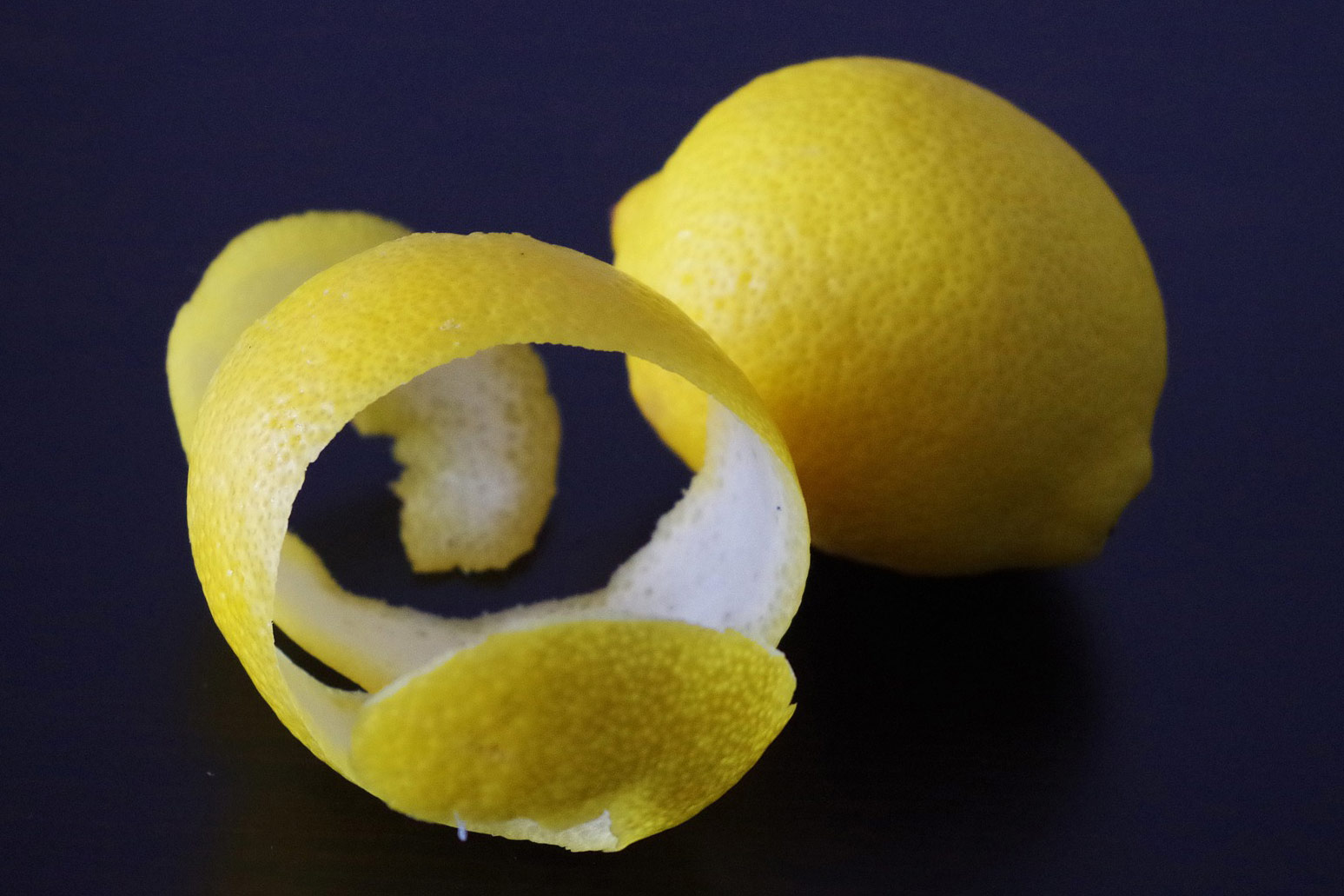 Fotografija prikazuje cijeli limun i koru oguljenu s limuna.