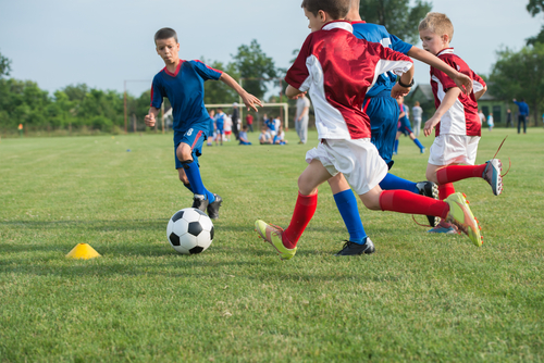 Slikom su prikazani dječaci koji igraju nogomet.