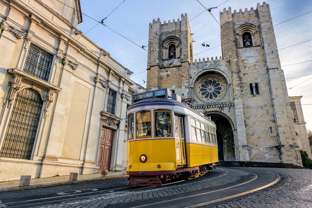 Slika prikazuje žuti tramvaj u Lisabonu.
