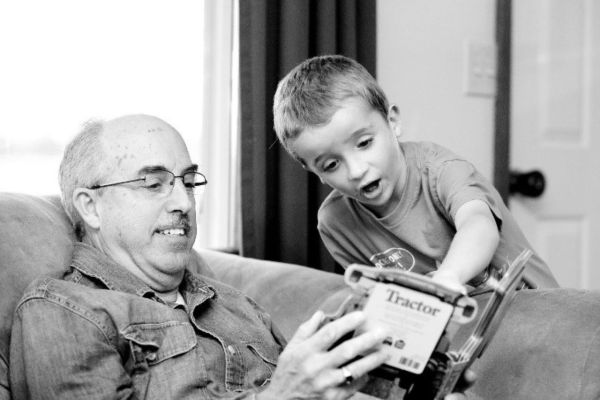 Slika prikazuje djeda i unuka kako razgovaraju.