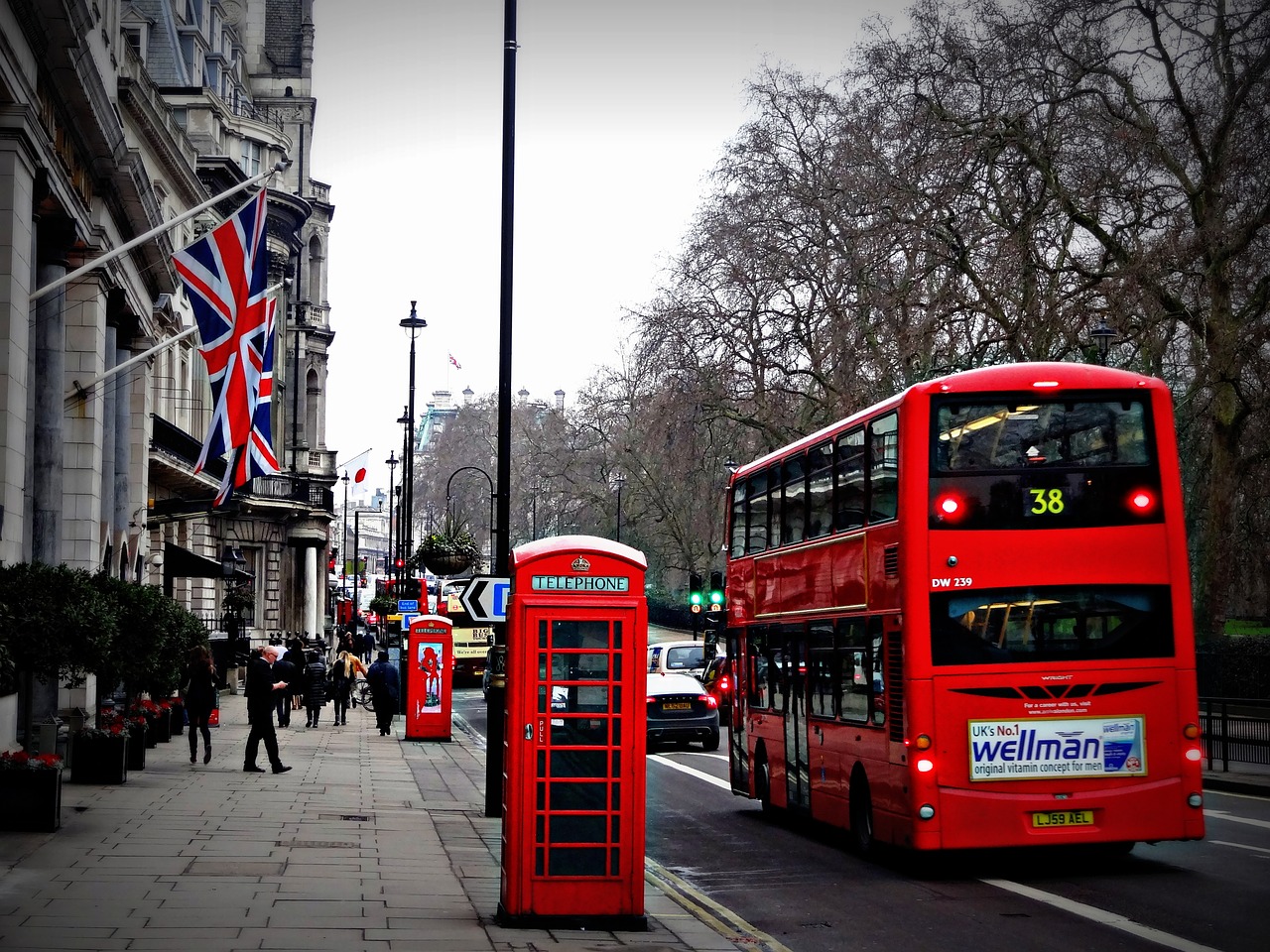 Na slici je prikazan crveni autobus i crvena telefonska govornica na ulici Londona.