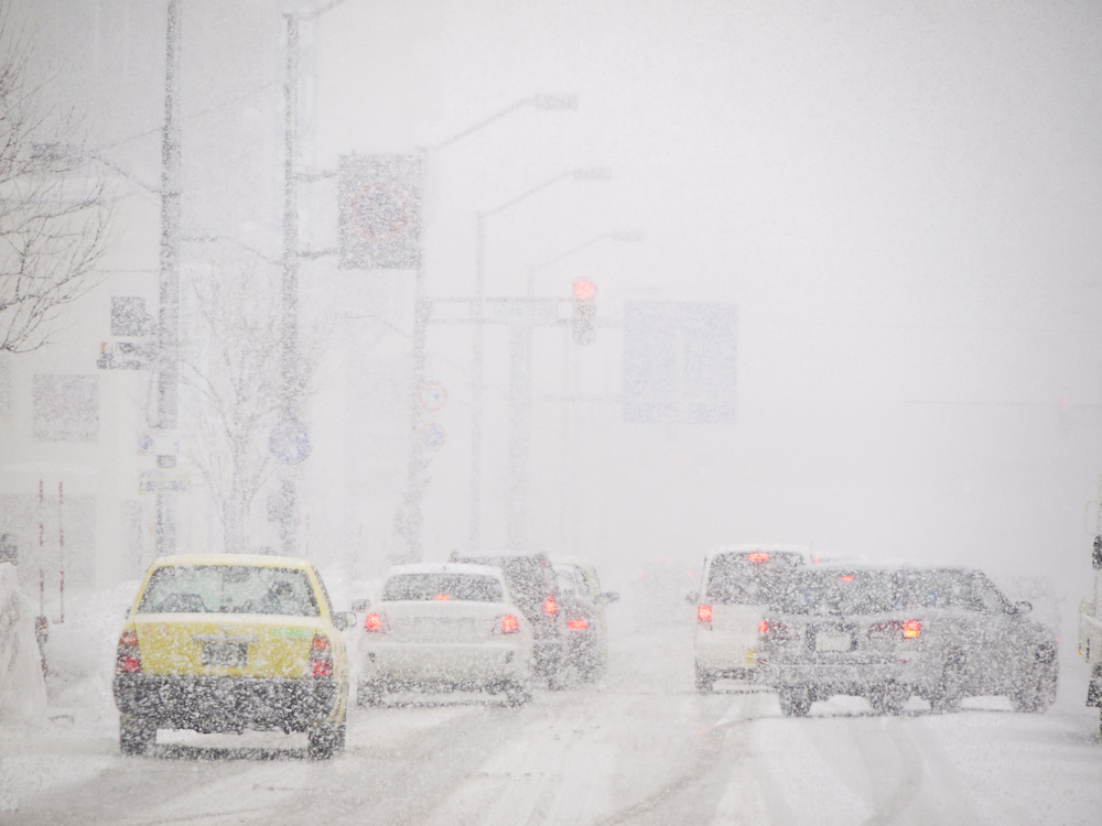 Slikom se prikazuje cesta s automobilima koji voze po snijegu.
