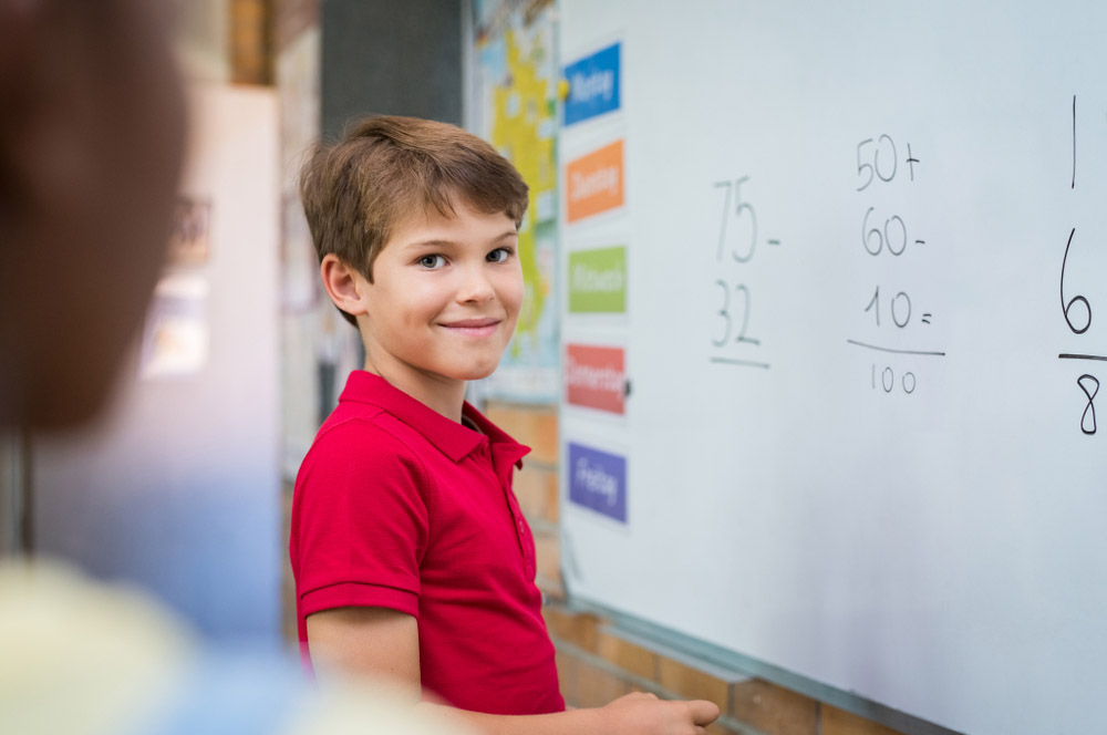 Slikom je prikazan dječak koji računa na školskoj ploči.