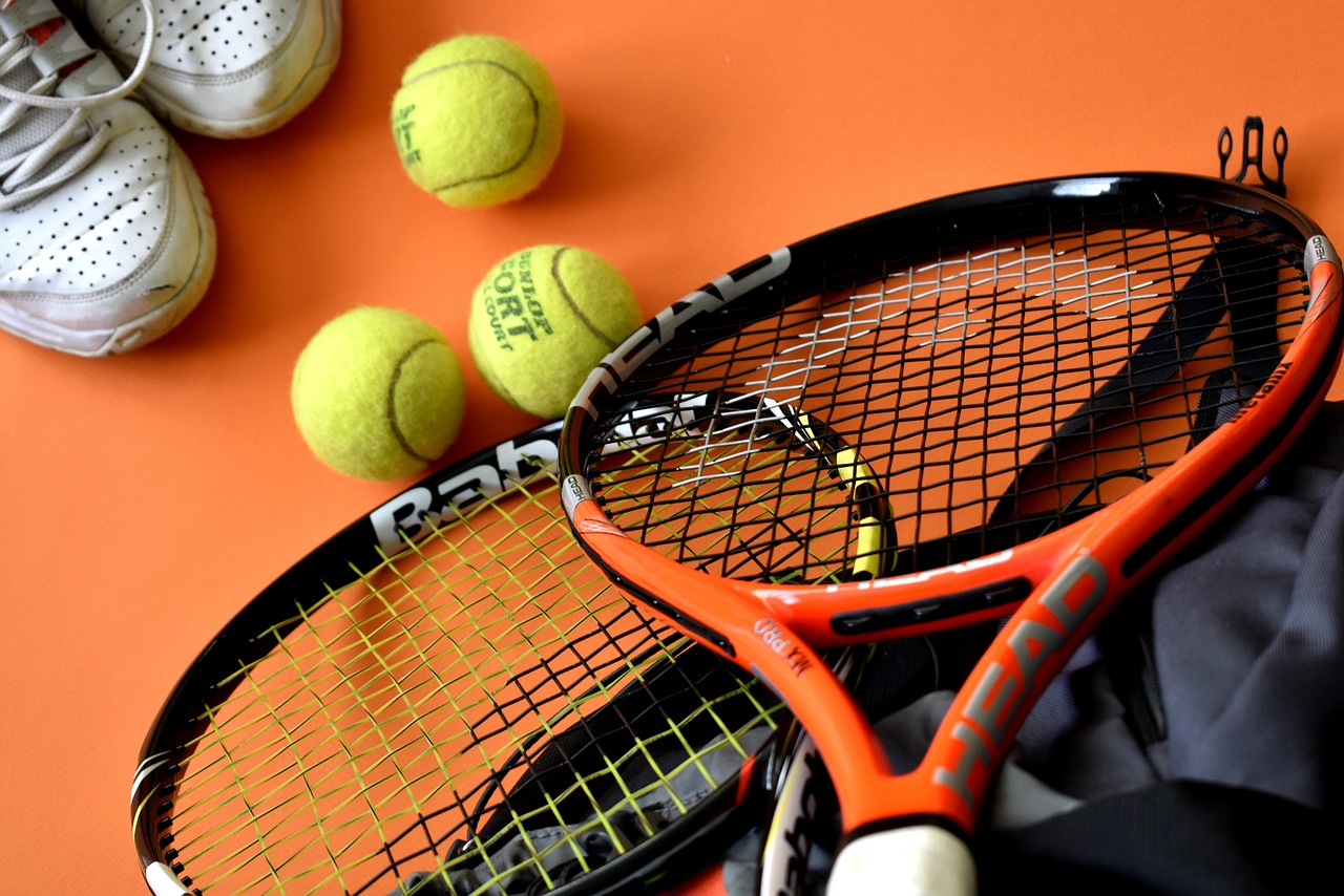Slikom su prikazani rekviziti za tenis: reketi, loptice i tenisice.