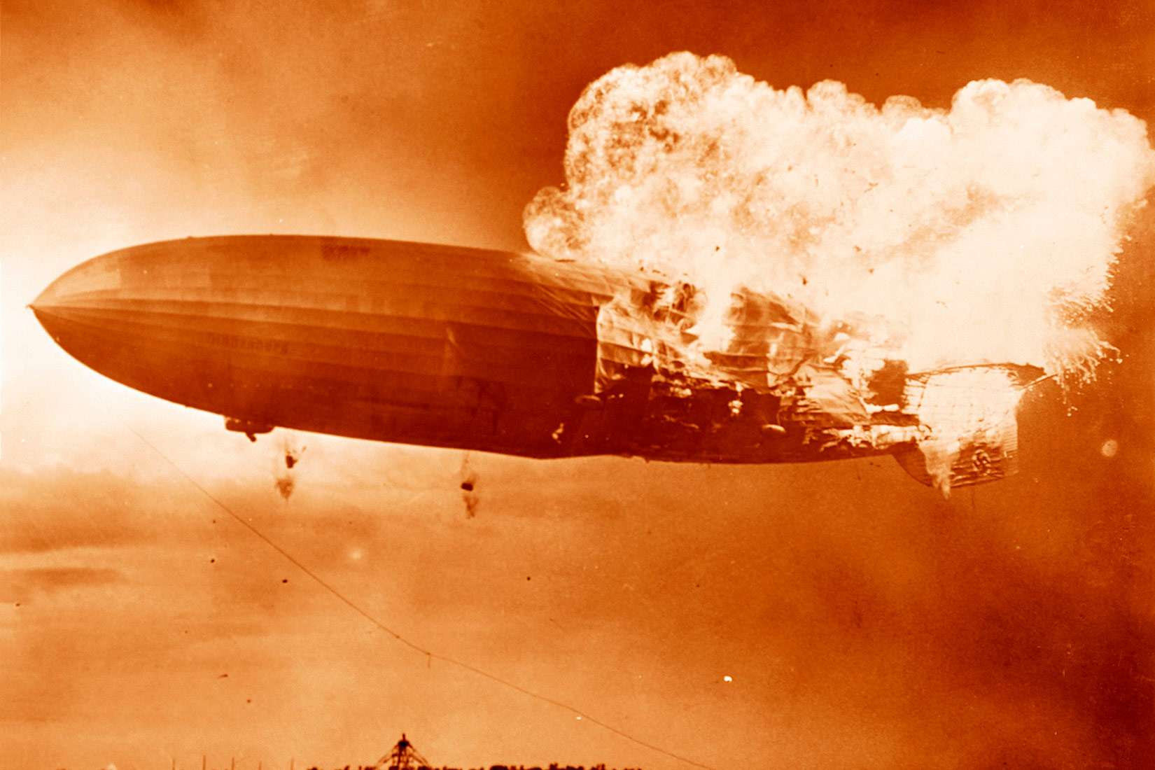 Na fotografiji je prikazana eksplzija putničkog cepelina Hindenburga. Njegov stražnji dio zahvačen je velikim plamenom, dok prednji dio još nije.Slika je prikazana u smeđim tonovima i svijetlećom buktinjom vatre.