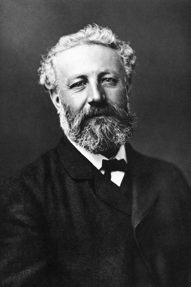 Na fotograiji je prikazan portret Jules Vernea. Fotografija je crno bijela. Verne ima sijedu kosu te gustu tamnu bradu i brkove prošarane sjedinama.