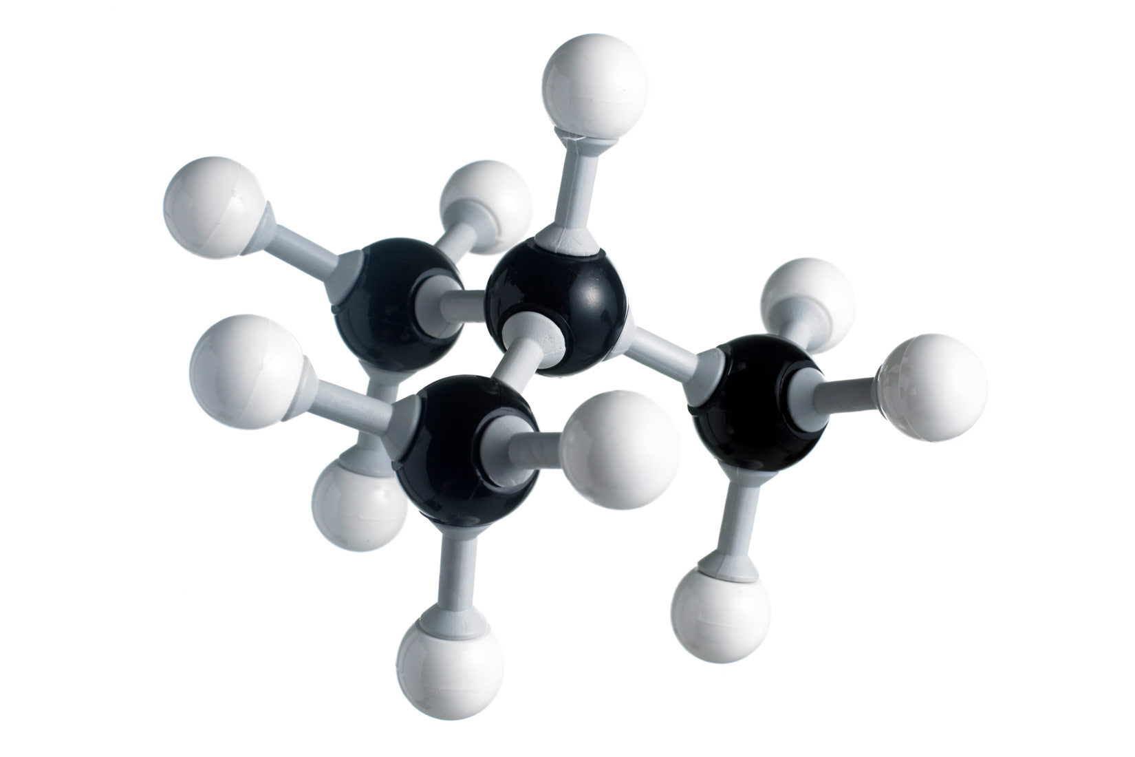Fotografija prikazuje molekulu butana načinjenu od kuglica i štapića. Molekula je razgranatog lanca. Tri atoma ugljika su u nizu. Od srednjeg atoma ugljika grana se četvrti atom ugljika. Svi atomi ugljika povezani su jednostrukim vezama s atomima vodika.