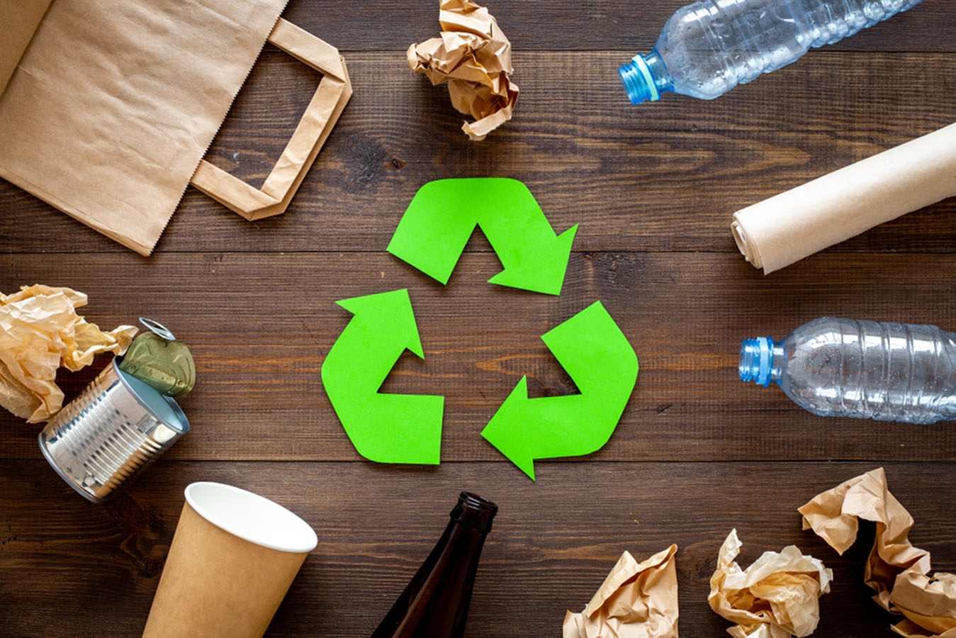 Na fotografiji je prikazan znak recikliranja i papirnate, plastične i limene ambalaže za recikliranje.