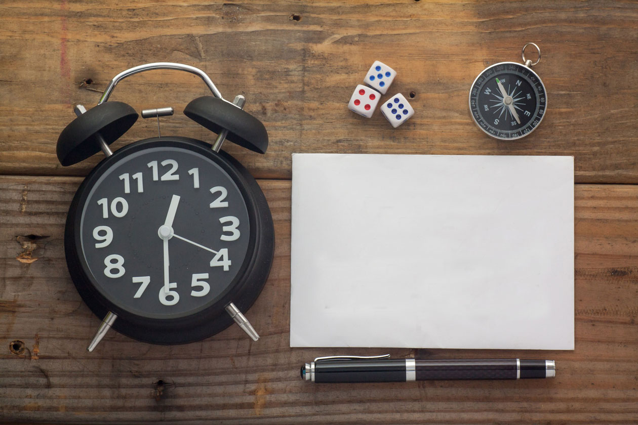 Slika prikazuje sat (uru), kompas, penkalu, blok papira i tri kockice za društvene igre.