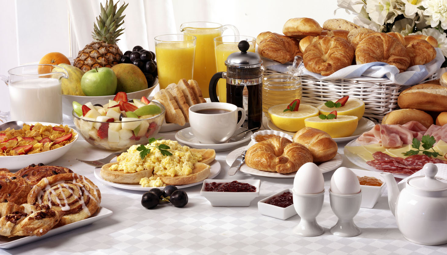 Slika prikazuje stol prepun hrane koja se jede za doručak.