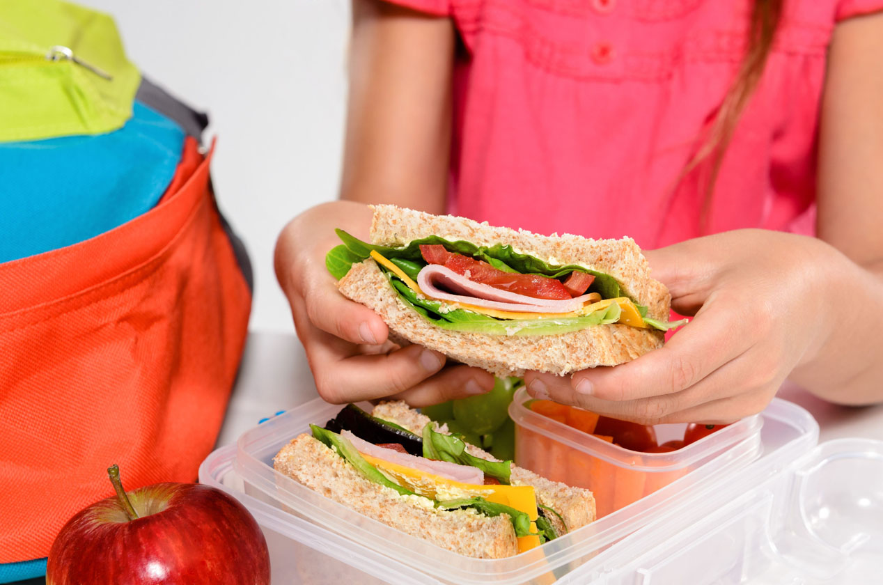 Slika prikazuje djevojčicu koja vadi svoju užinu (sendvič) iz kutije.Slika prikazuje djevojčicu koja vadi svoju užinu (sendvič) iz kutije.