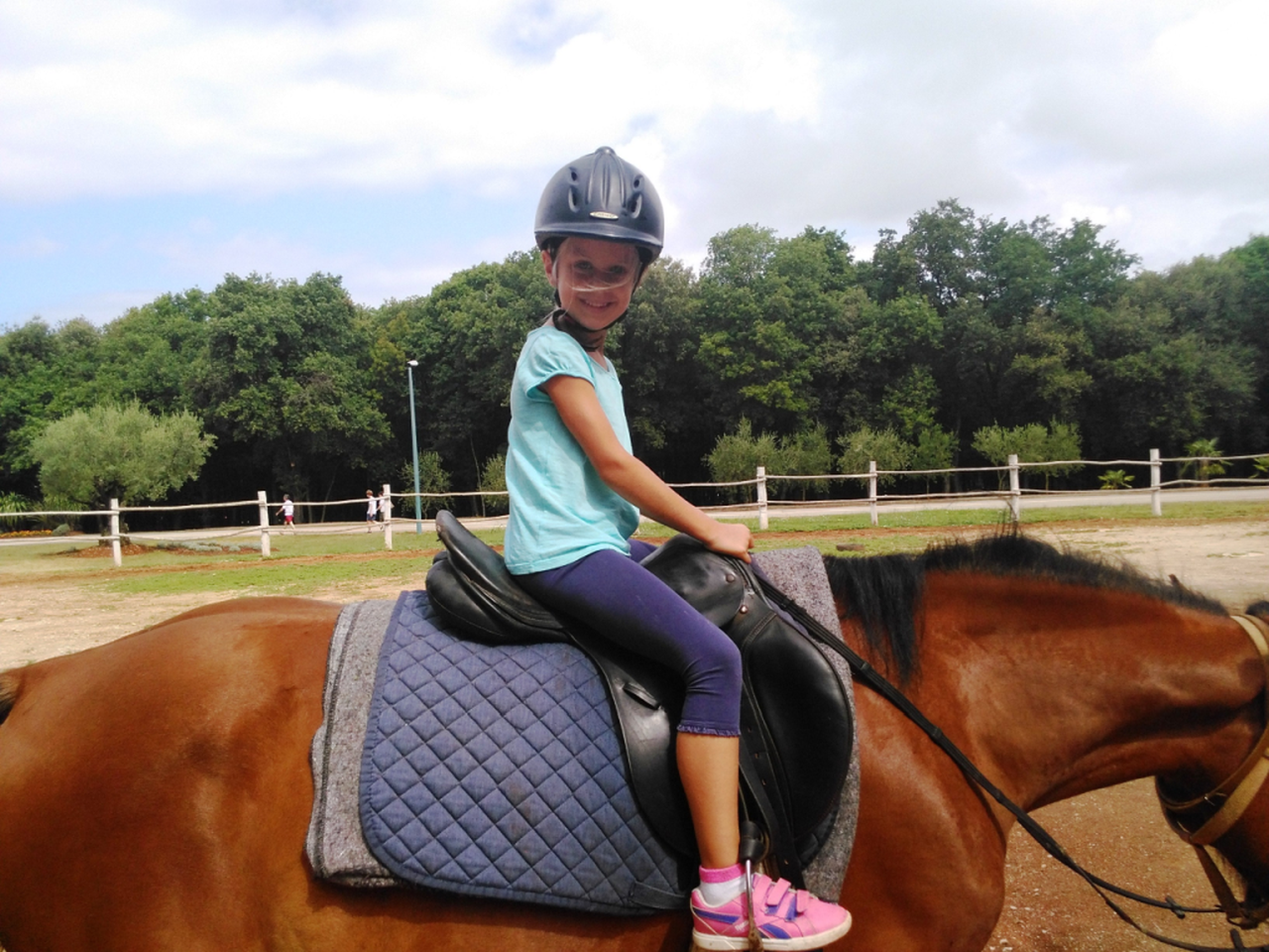Na fotografiji je prikazana djevojčica koja jaše konja.