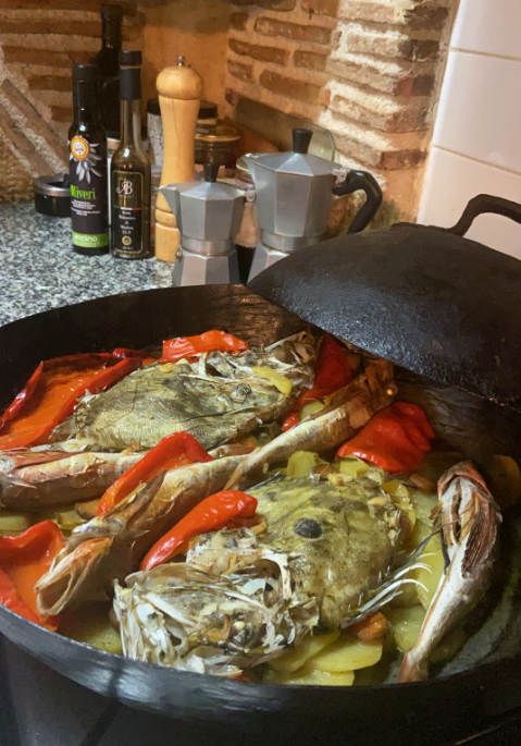 Slika prikazuje ribu kovač s krumpirom i paprikom pečenu pod zvonom.