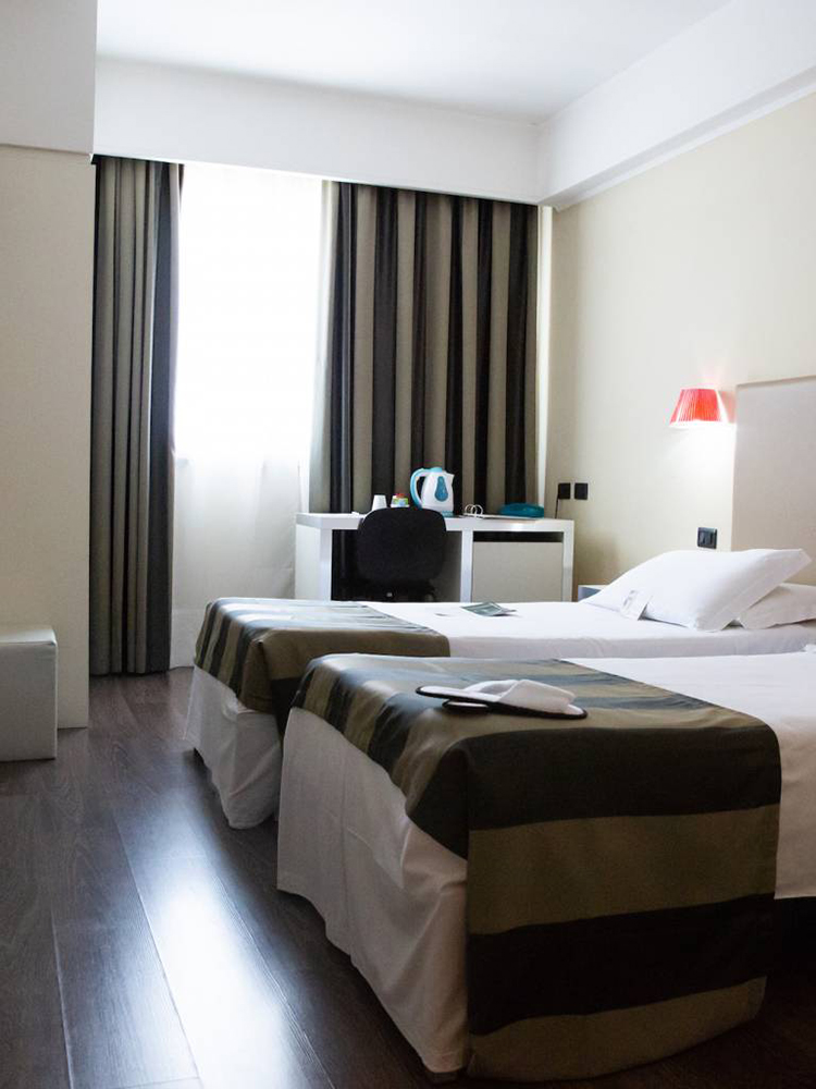 Na fotografiji je prikazana dvokrevetna hotelska soba s odvojenim krevetima.