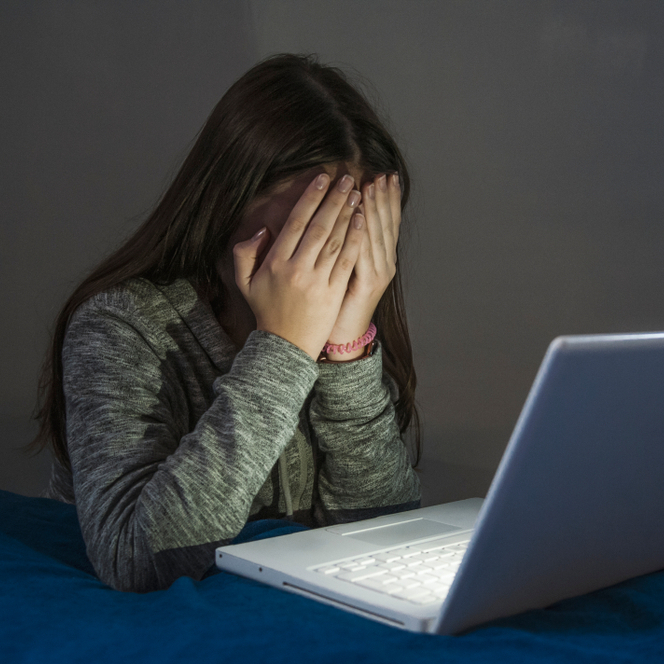 Slika prikazuje djevojčicu pred laptopom koja je žrtva cybermobbinga