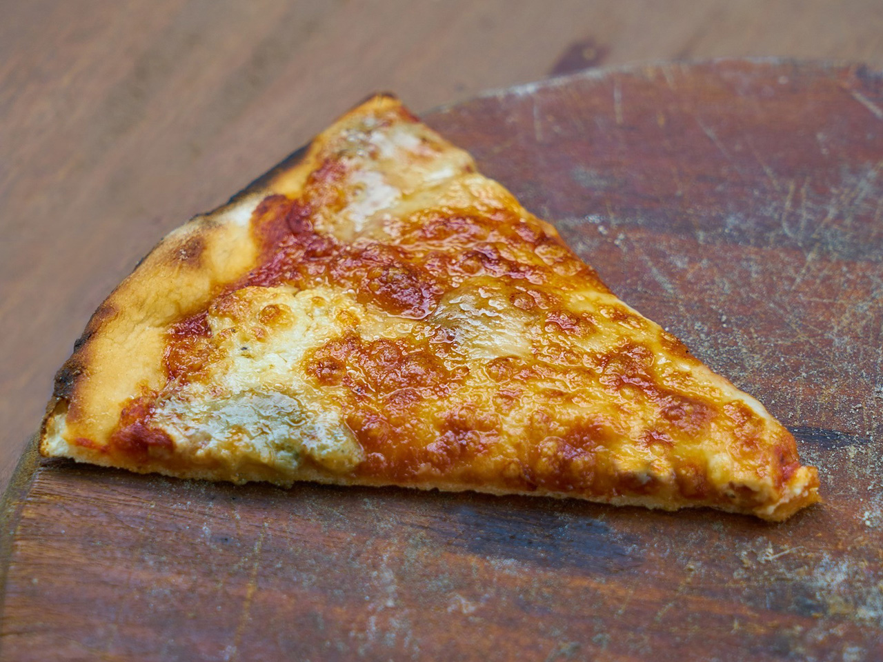 Trokut pizze na drvenom podlošku.