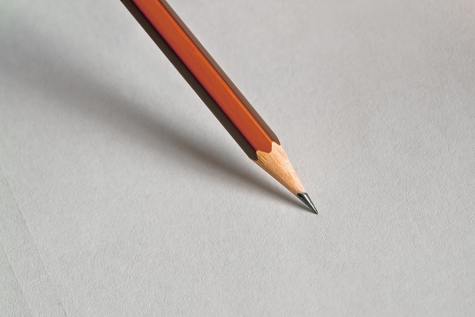 Fotografija prikazuje olovku i papir, olovka je u kosom položaju prema ravnini papira.