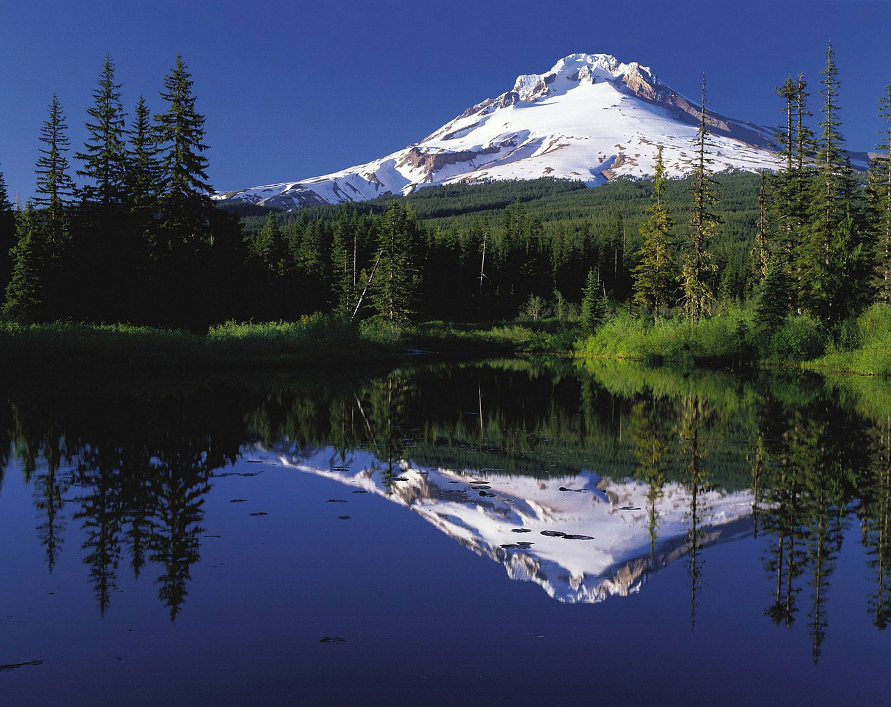Fotografija prikazuje planinu i njezin odraz u jezeru.