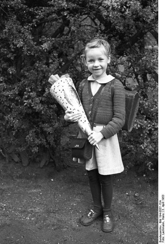 Slika prikazuje djevojčicu koja u rukama drži stožac sa slatkišima.