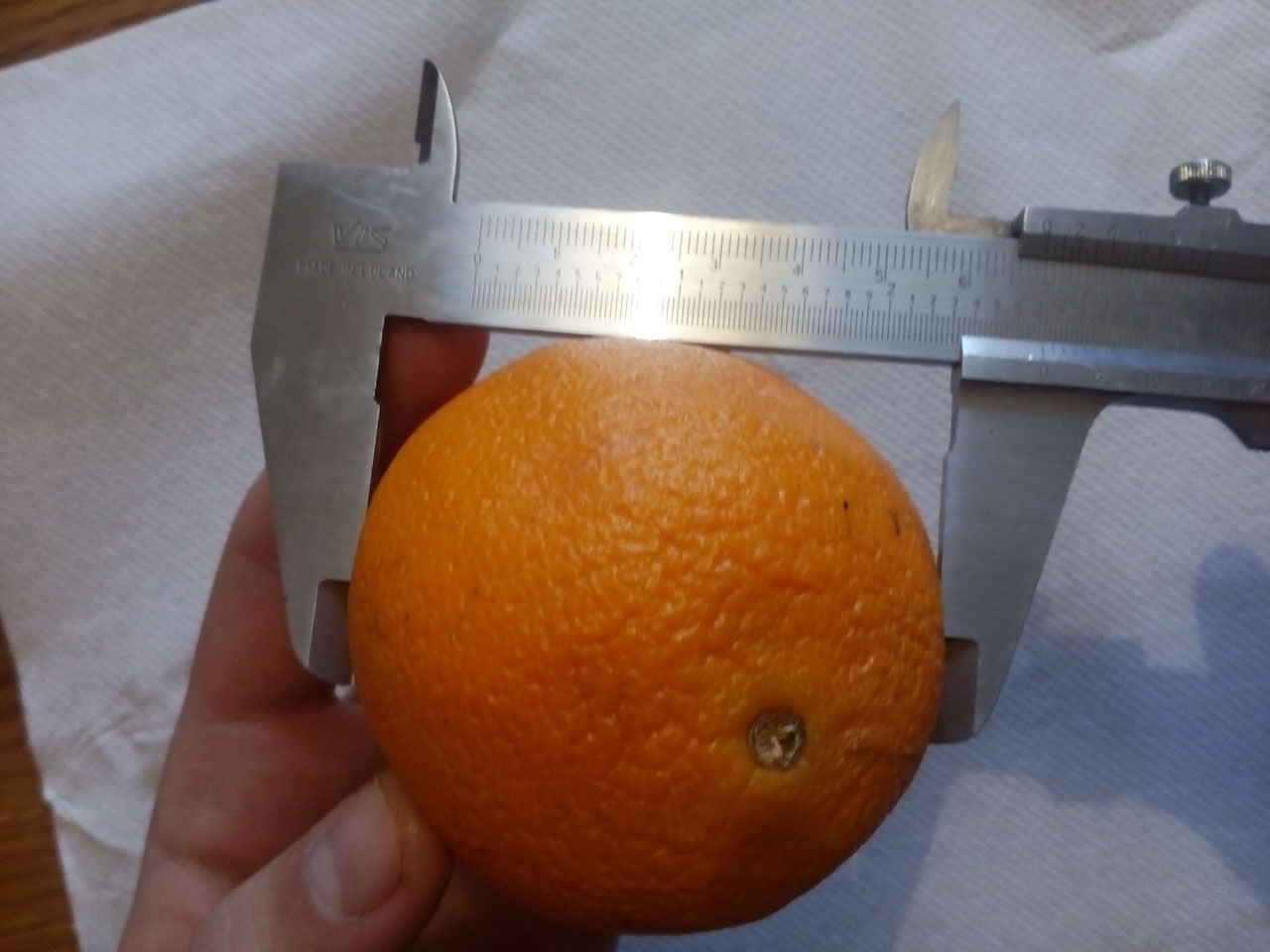 Slika prikazuje mjerenje promjera naranče pomičnom mjerkom