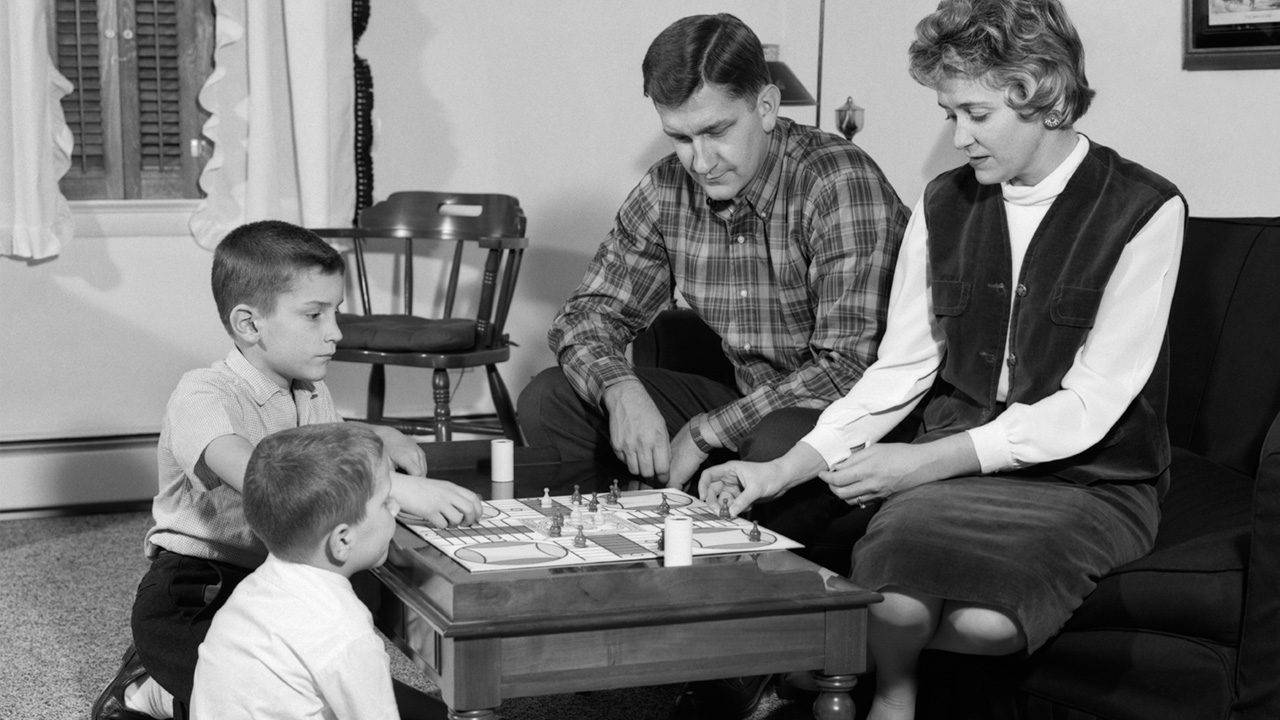 Otac, majka i dva sina igraju društvenu igru. 