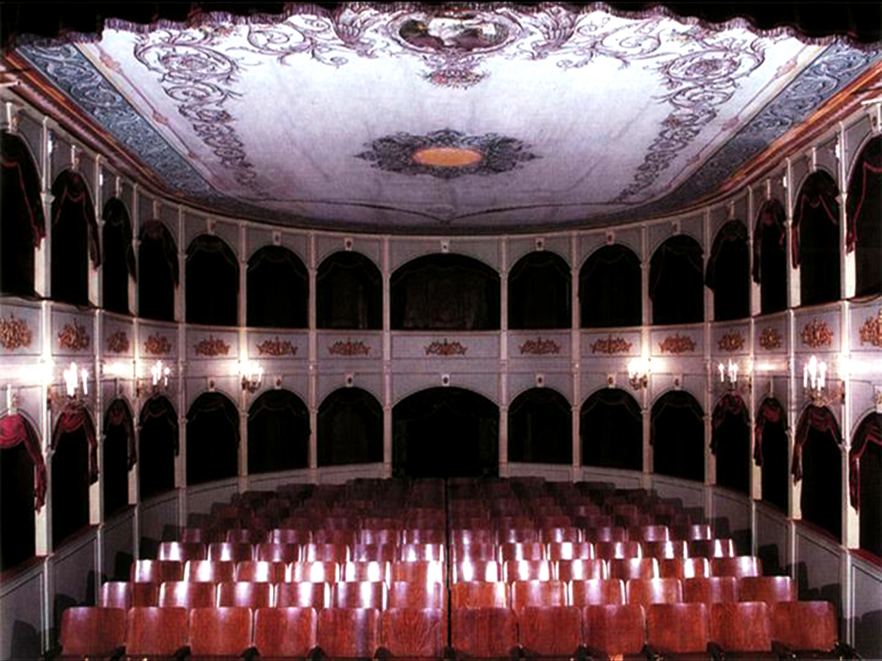 Unutrašnjost najstarijeg hrvatskog kazališta u Hvaru s drvenim stolicama te ložama u prizemlju i na katu.