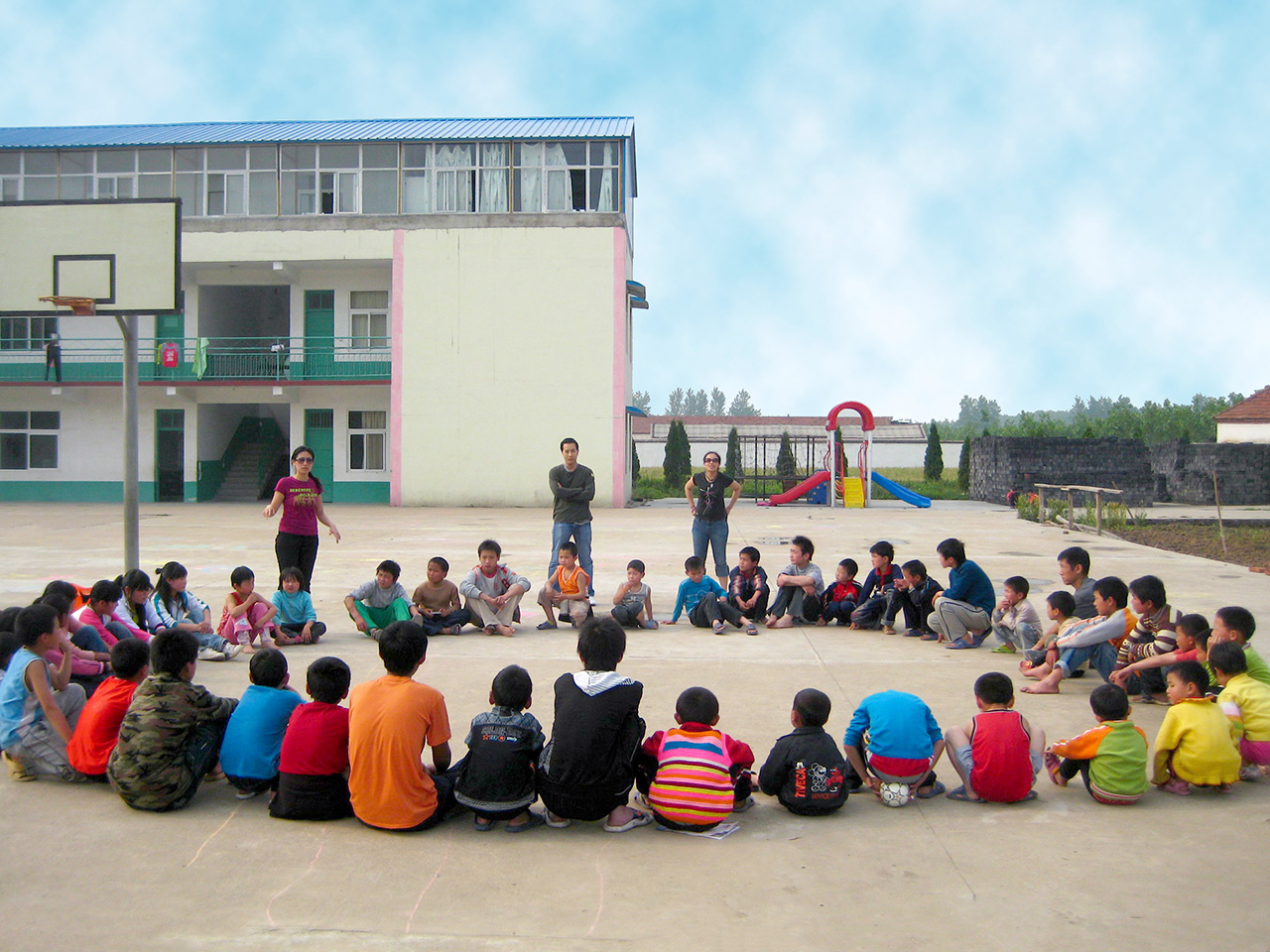 Skupina učenika sjedi u krugu na školskom igralištu i razgovara.