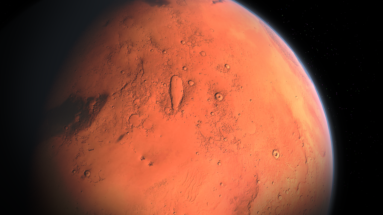 Fotografija prikazuje planet Mars. Prikazan je zumirani dio planeta.Vidi se crvena površina, a pozadina je crne boje.
