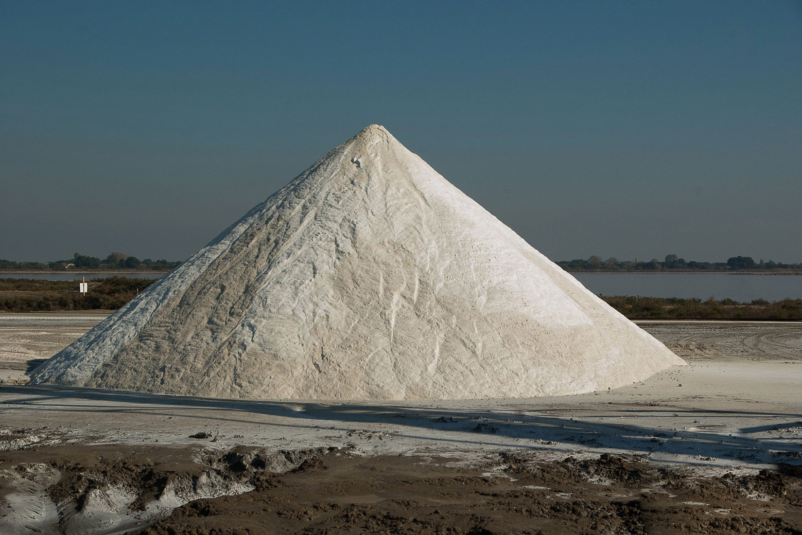 Fotografija prikazuje veliku količinu morske soli u solani koja je posložena u obliku stožca.