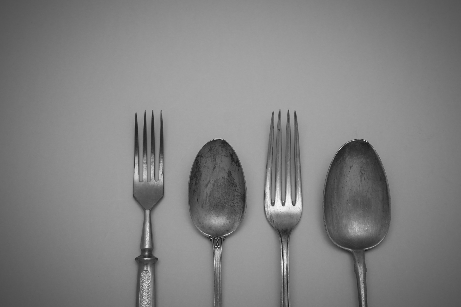 Fotografija prikazuje pribor za jelo, dvije vilice i žlice načinjene od srebra.
